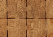 Dettaglio macro di blocchi di legno grezzo che si incastrano perfettamente tra loro, creando una struttura solida e simmetrica.