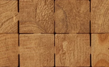 Dettaglio macro di blocchi di legno grezzo che si incastrano perfettamente tra loro, creando una struttura solida e simmetrica.