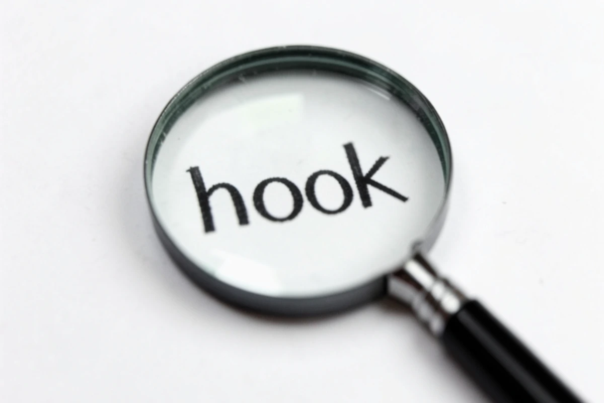 Una lente di ingrandimento appoggiata su un foglio bianco che rende nitida la parola "hook" scritta in nero. 