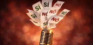 Un microfono da festival che emerge da un'urna elettorale con schede "Sì" e "No" che volano.