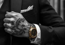 Primo piano cinematografico di una mano tatuata che stringe il bavero di una giacca sartoriale di alta qualità, con un orologio al polso, su uno sfondo di un vicolo urbano sfocato con graffiti.